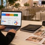 Profesional del sector bodas y eventos trabajando una estrategia de publicidad digital en un espacio elegante de celebración con portátil, cámara y elementos de planificación visual.